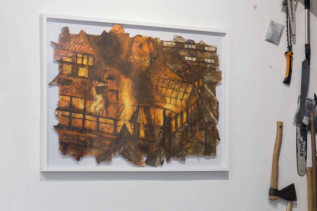 painting of burning building next to tools on wall